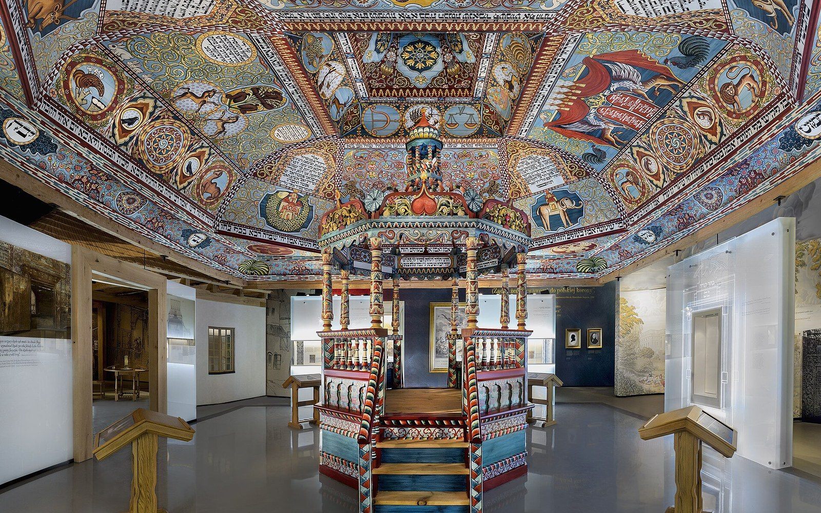An adult visitor standing beneath the reconstructed Gwoździec painted ceiling installed in the POLIN Museum, Warsaw, 2014, looking upward