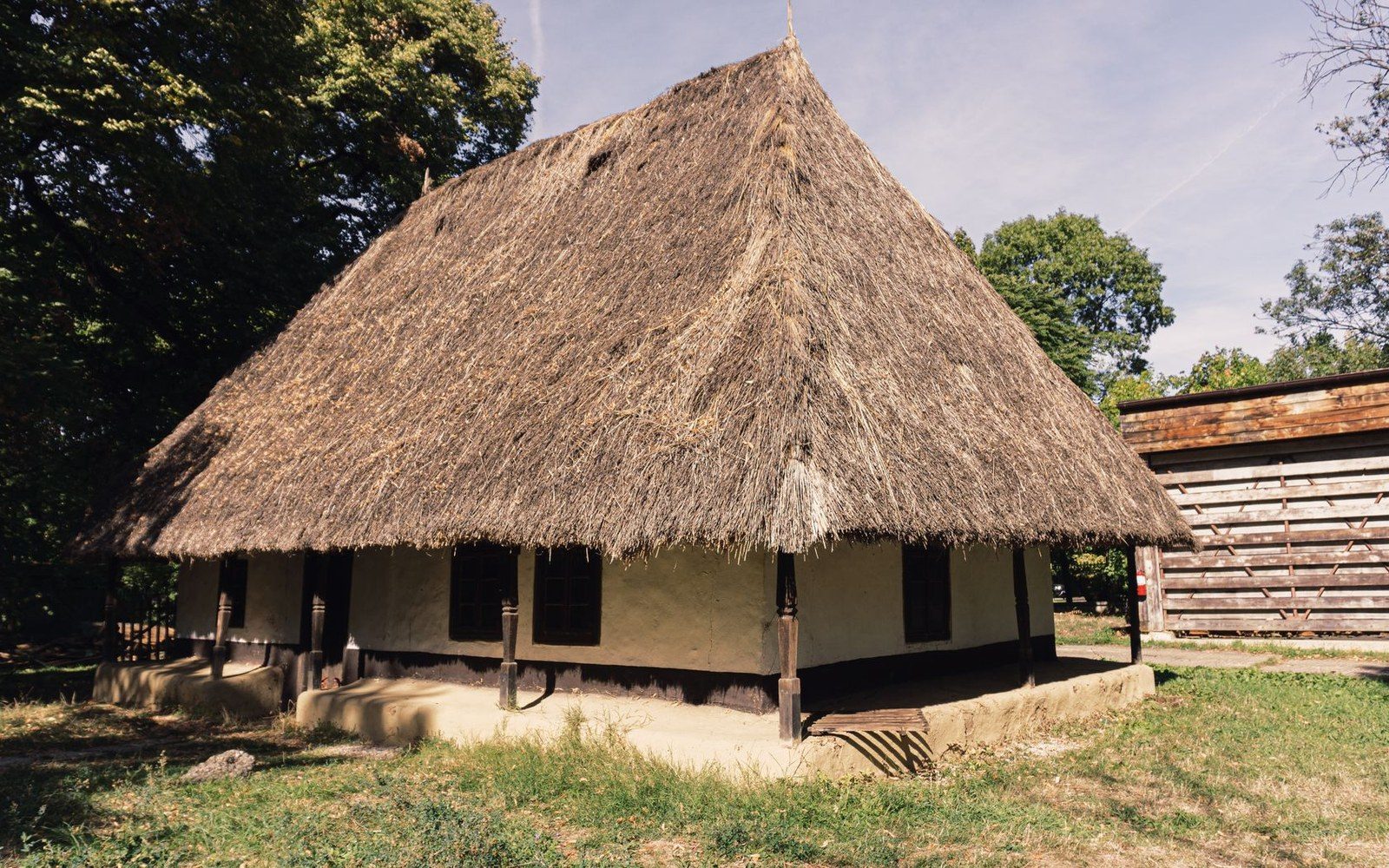 Adult craftspeople raising a full-size timber frame in the open-air museum workshop at Sanok, viewed from below the assembled truss